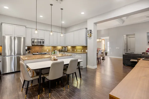 a kitchen with stainless steel appliances a dining table chairs refrigerator and microwave