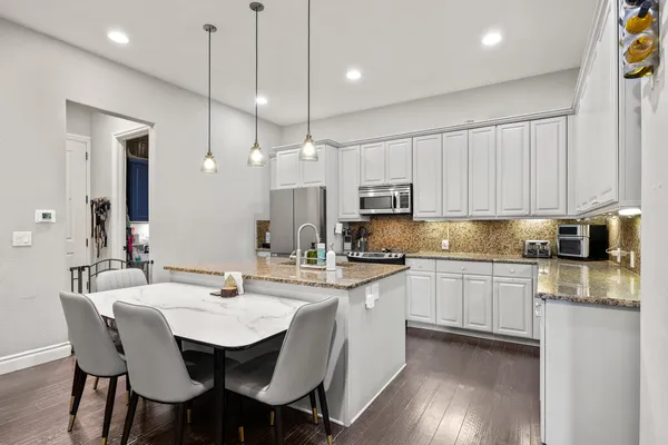 a kitchen with stainless steel appliances kitchen island granite countertop a sink a stove a dining table and chairs