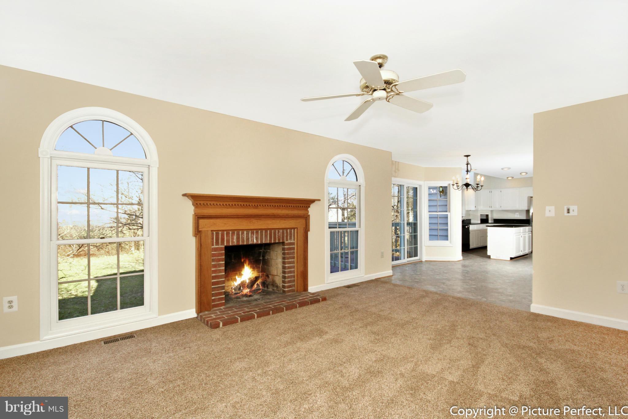 19111 Munger Farm Road Poolesville, MD 20837 - Photo 12 of 30 a view of a livingroom with a fireplace a ceiling fan and windows