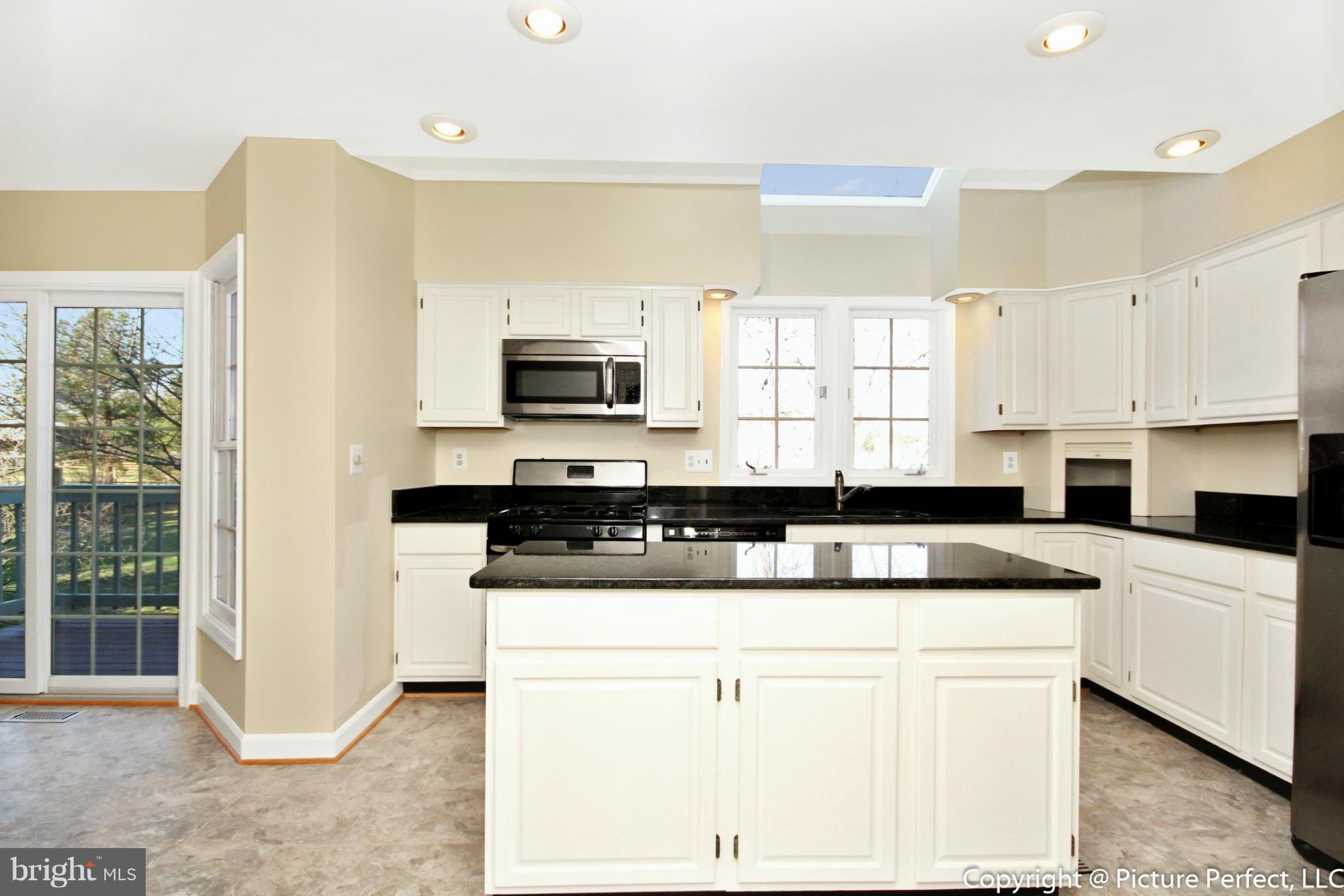 19111 Munger Farm Road Poolesville, MD 20837 - Photo 17 of 30 a kitchen with stainless steel appliances granite countertop a sink a stove a refrigerator a microwave and white cabinets