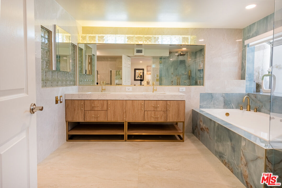 31271 Bailard Road Malibu, CA 90265 - Photo 16 of 38 a bathroom with a tub a double vanity sink and mirror