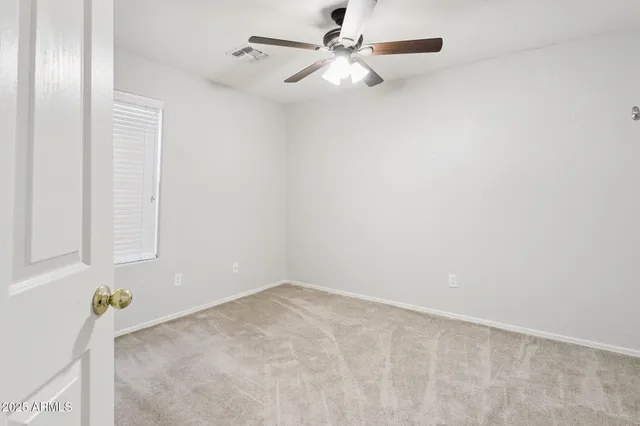 an empty room with a window and ceiling fan