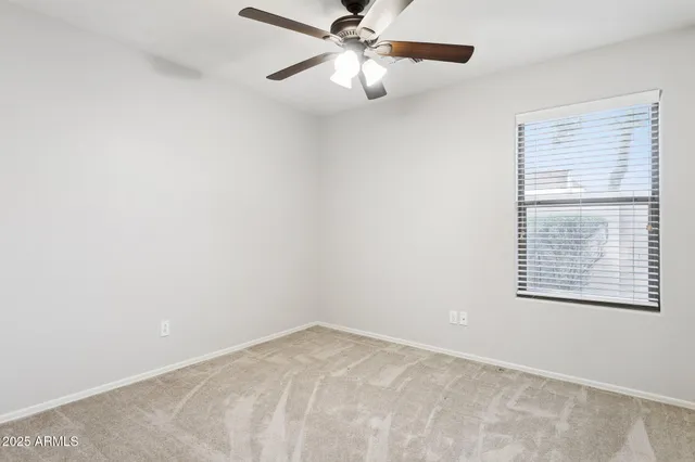 an empty room with a window and a fan