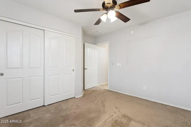 an empty room with closet and a chandelier fan