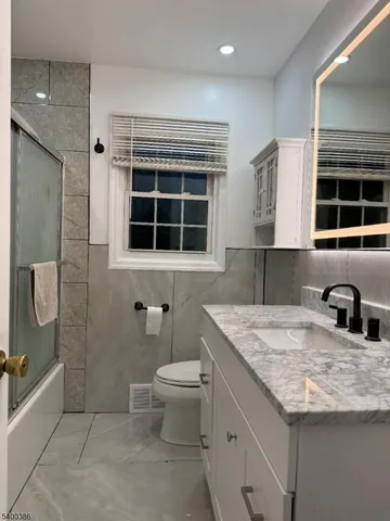 a bathroom with a granite countertop sink toilet and shower
