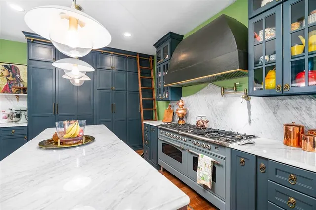 a kitchen with stainless steel appliances a stove a chimney and a dining table