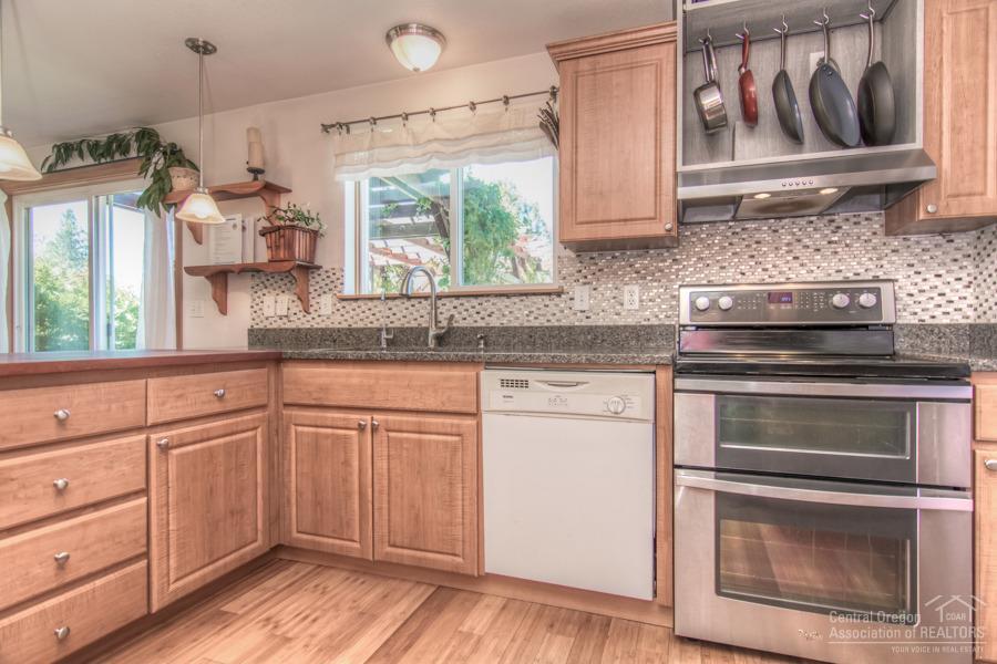 19548 Apache Road Bend, OR 97702 - Photo 6 of 25 a kitchen with granite countertop white cabinets and white appliances