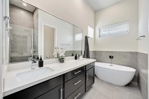 a bathroom with a double vanity sink mirror and bathtub