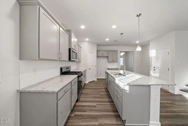 a large kitchen with kitchen island a stove a sink a refrigerator and a wooden floor