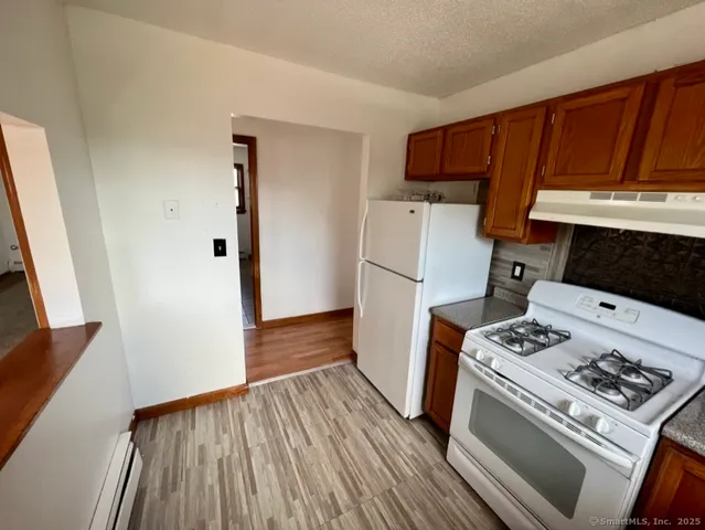 a kitchen with a stove a refrigerator and wooden floor