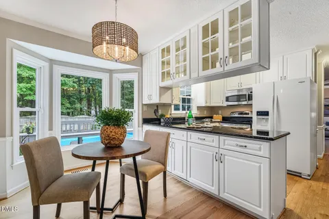 a kitchen with stainless steel appliances granite countertop a dining table chairs and a refrigerator