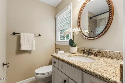 a bathroom with a granite countertop toilet a sink and a mirror