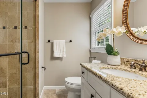 a bathroom with a granite countertop sink a toilet and shower