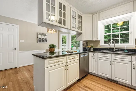 a kitchen with stainless steel appliances granite countertop a sink and cabinets with wooden floor