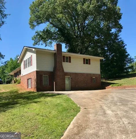 a front view of house with yard and trees in the background