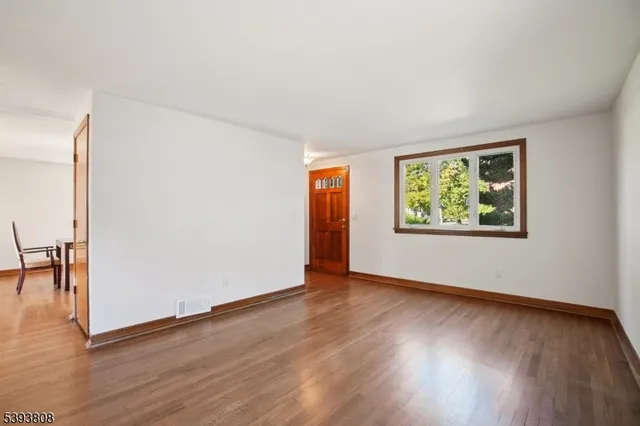 an empty room with wooden floor and window