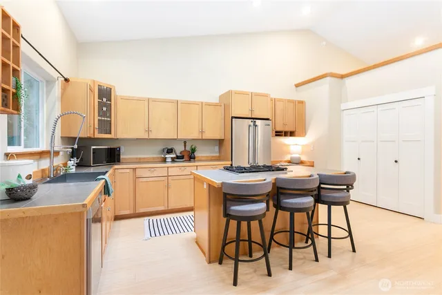 a kitchen with stainless steel appliances kitchen island granite countertop a table chairs and a refrigerator