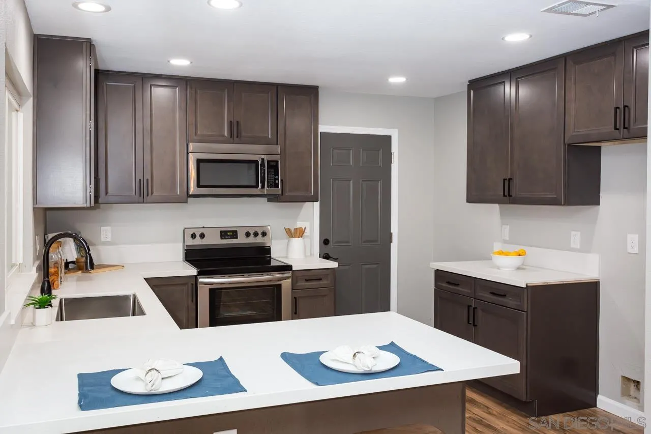 11834 Rocoso Road Lakeside, CA 92040 - Photo 14 of 28 a kitchen with a stove a microwave and wooden cabinets