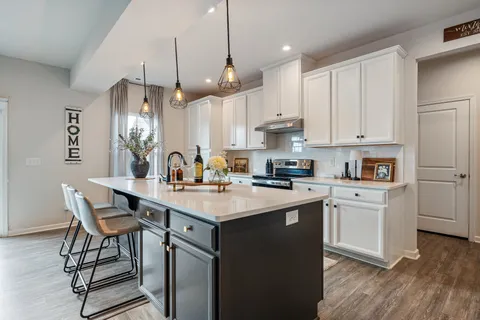 a kitchen with stainless steel appliances granite countertop a sink a stove a refrigerator and island with wooden floor