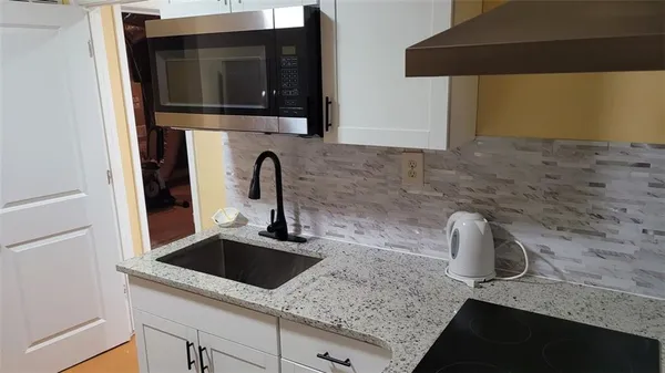 a kitchen with granite countertop a sink and a stove top oven