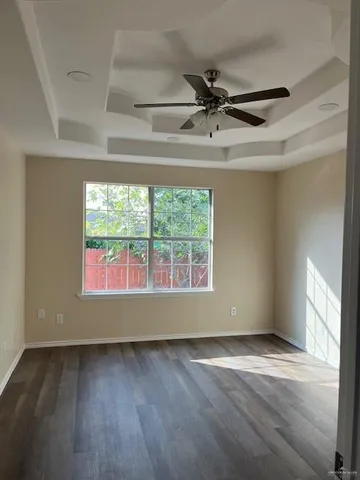 an empty room with wooden floor fan and windows
