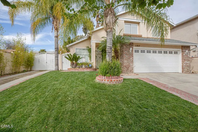 a view of a house with a yard and palm trees
