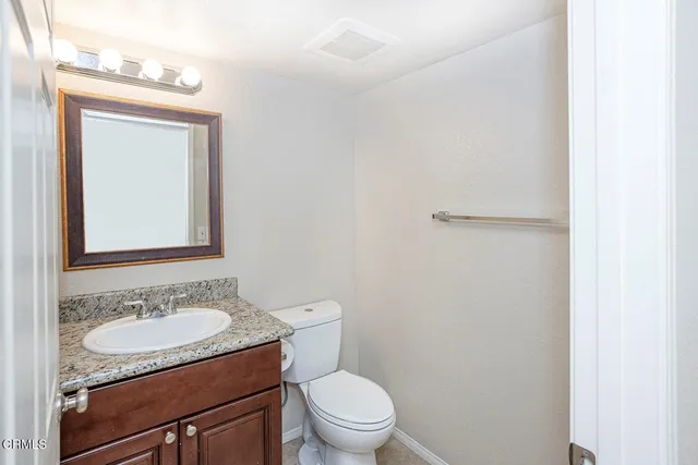 a bathroom with a granite countertop sink toilet and mirror