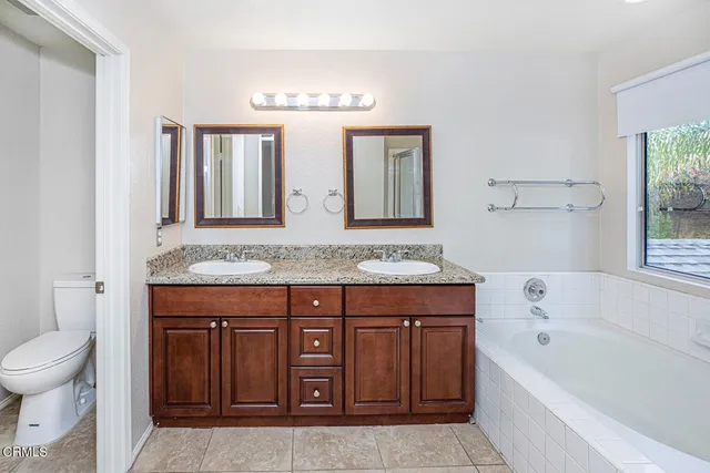 a bathroom with a granite countertop sink a toilet and bathtub