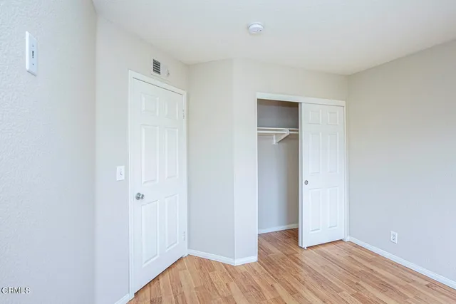 a view of an empty room with closet and wooden floor