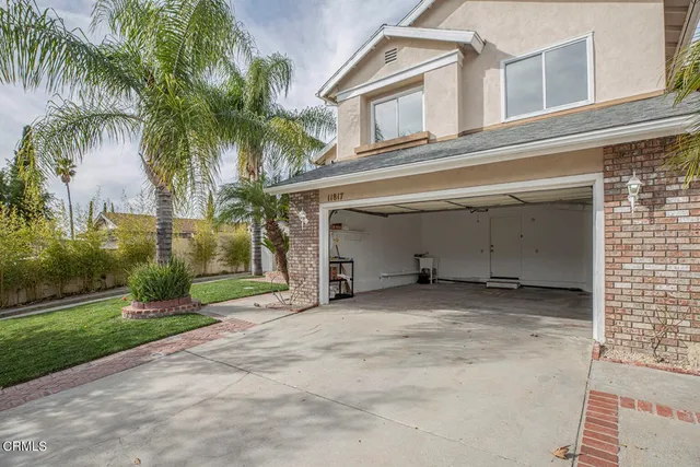 a view of a house with a yard and palm trees