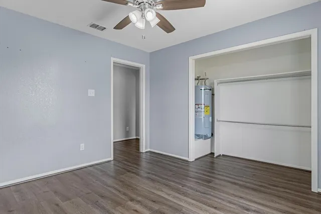 an empty room with wooden floor cabinet and a hallway