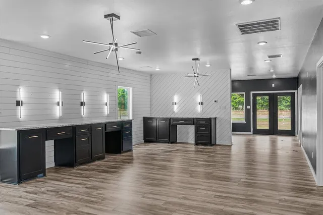 a large kitchen with stainless steel appliances granite countertop a stove top oven a sink dishwasher a dining table and chairs with wooden floor