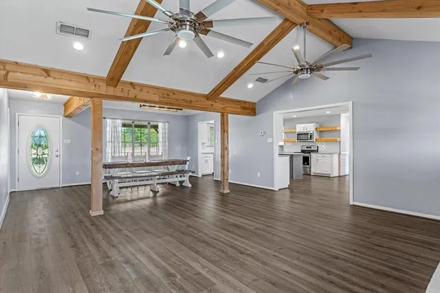 an empty room with wooden floor table and chairs