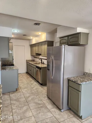 a kitchen with stainless steel appliances granite countertop a refrigerator a stove and a sink