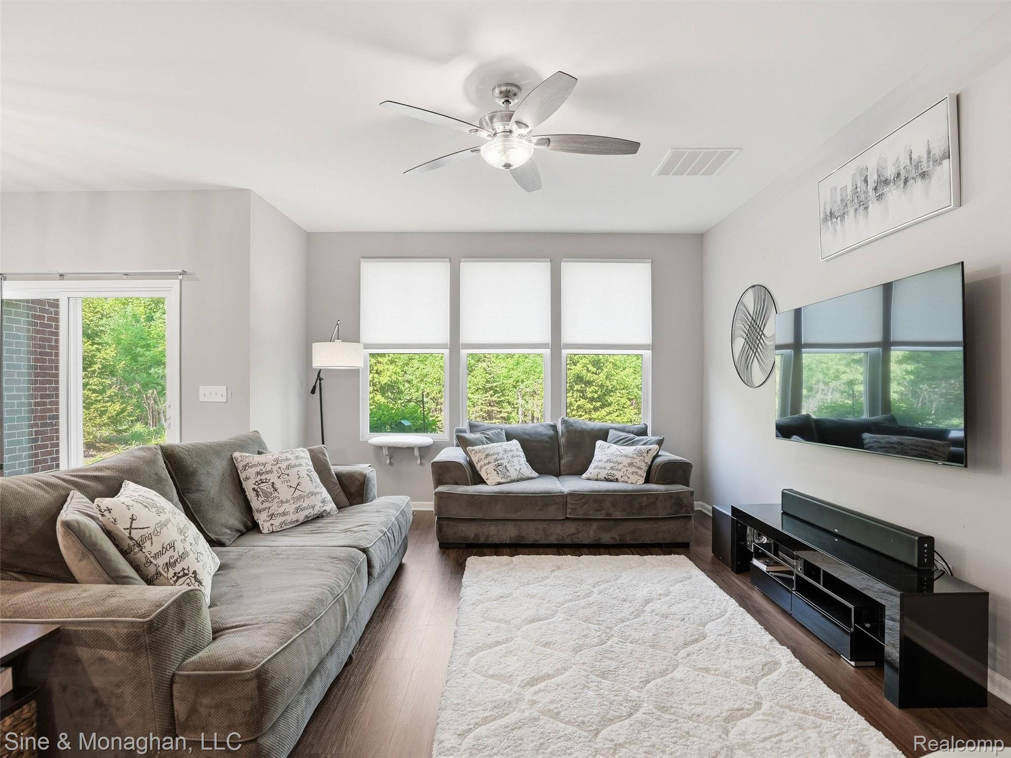 24827 Ivy Road Novi, MI 48375 - Photo 11 of 38 Spacious living area featuring wood-finish flooring, light gray walls, a ceiling fan with integrated lighting, and multiple windows providing natural illumination