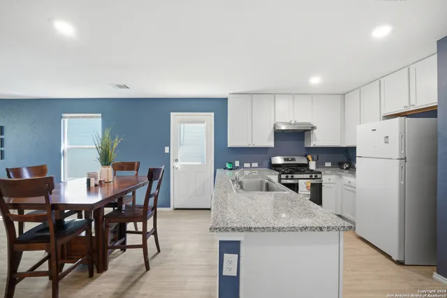 a kitchen with granite countertop stainless steel appliances a table and chairs in it