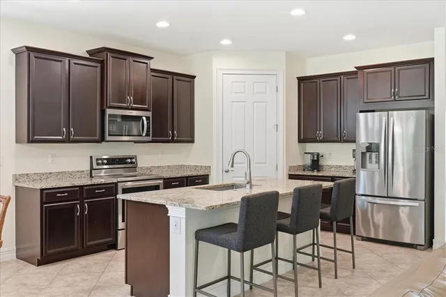 a kitchen with stainless steel appliances granite countertop a stove a sink dishwasher a refrigerator and a microwave