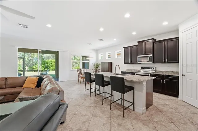 a living room with stainless steel appliances furniture and a kitchen view