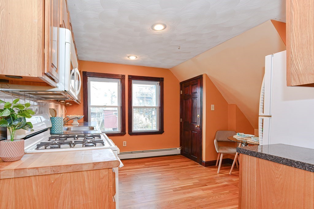 64 Hyde Park Avenue, Unit 3 Boston, MA 02130 - Photo 9 of 27 a kitchen that has a stove and a table chair in it