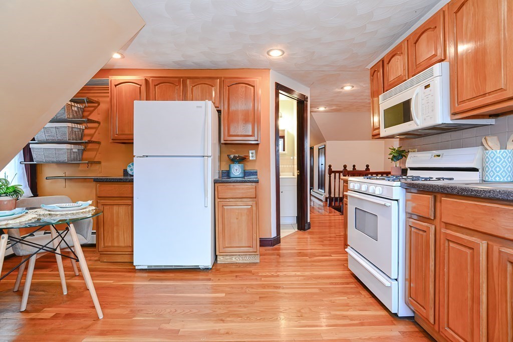 64 Hyde Park Avenue, Unit 3 Boston, MA 02130 - Photo 10 of 27 a kitchen with stainless steel appliances kitchen island granite countertop a refrigerator a stove and a wooden floors