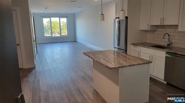 a kitchen with granite countertop a sink and a refrigerator