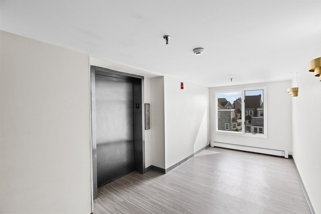 1 Commodore Court, Unit 305 Hull, MA 02045 - Photo 21 of 27 an empty room with wooden floor and windows