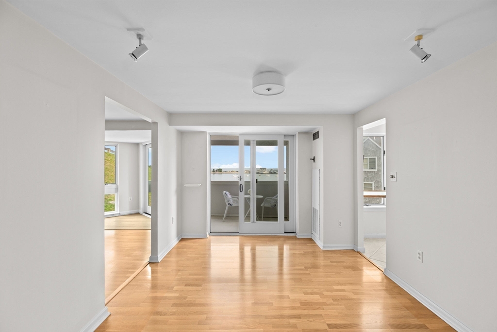 1 Commodore Court, Unit 305 Hull, MA 02045 - Photo 10 of 27 a view of an empty room with wooden floor and a window