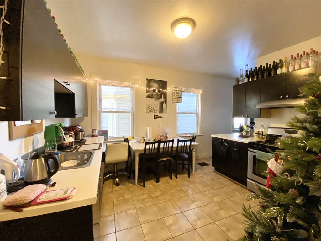 72 Calumet Street, Unit 1 Boston, MA 02120 - Photo 2 of 8 a large white kitchen with chairs a stove and a dining table