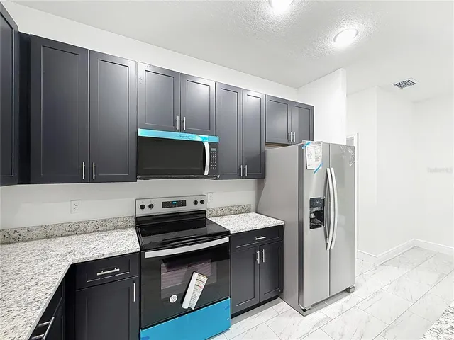 a kitchen with stainless steel appliances granite countertop a refrigerator and a stove top oven
