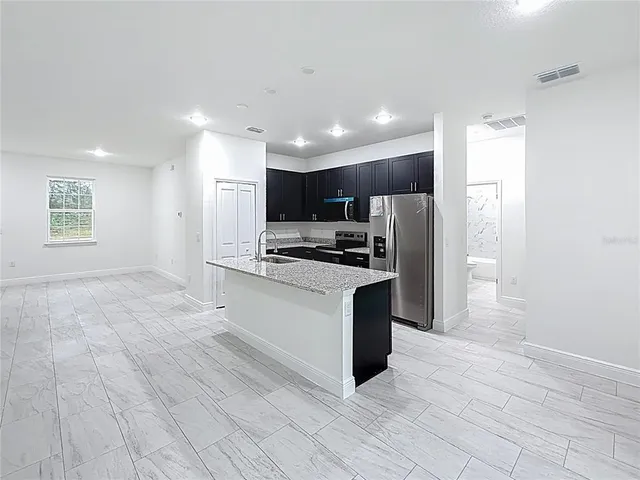 a kitchen with stainless steel appliances kitchen island granite countertop a refrigerator and a stove top oven