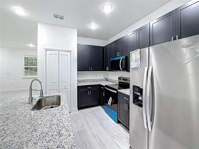 a kitchen with granite countertop a refrigerator and a sink