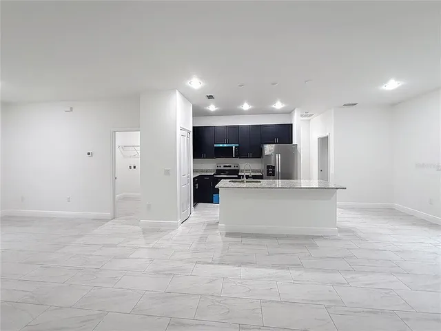 a view of kitchen with kitchen island stainless steel appliances a sink and cabinets