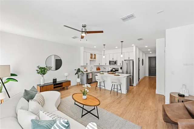 a living room with furniture kitchen view and a chandelier