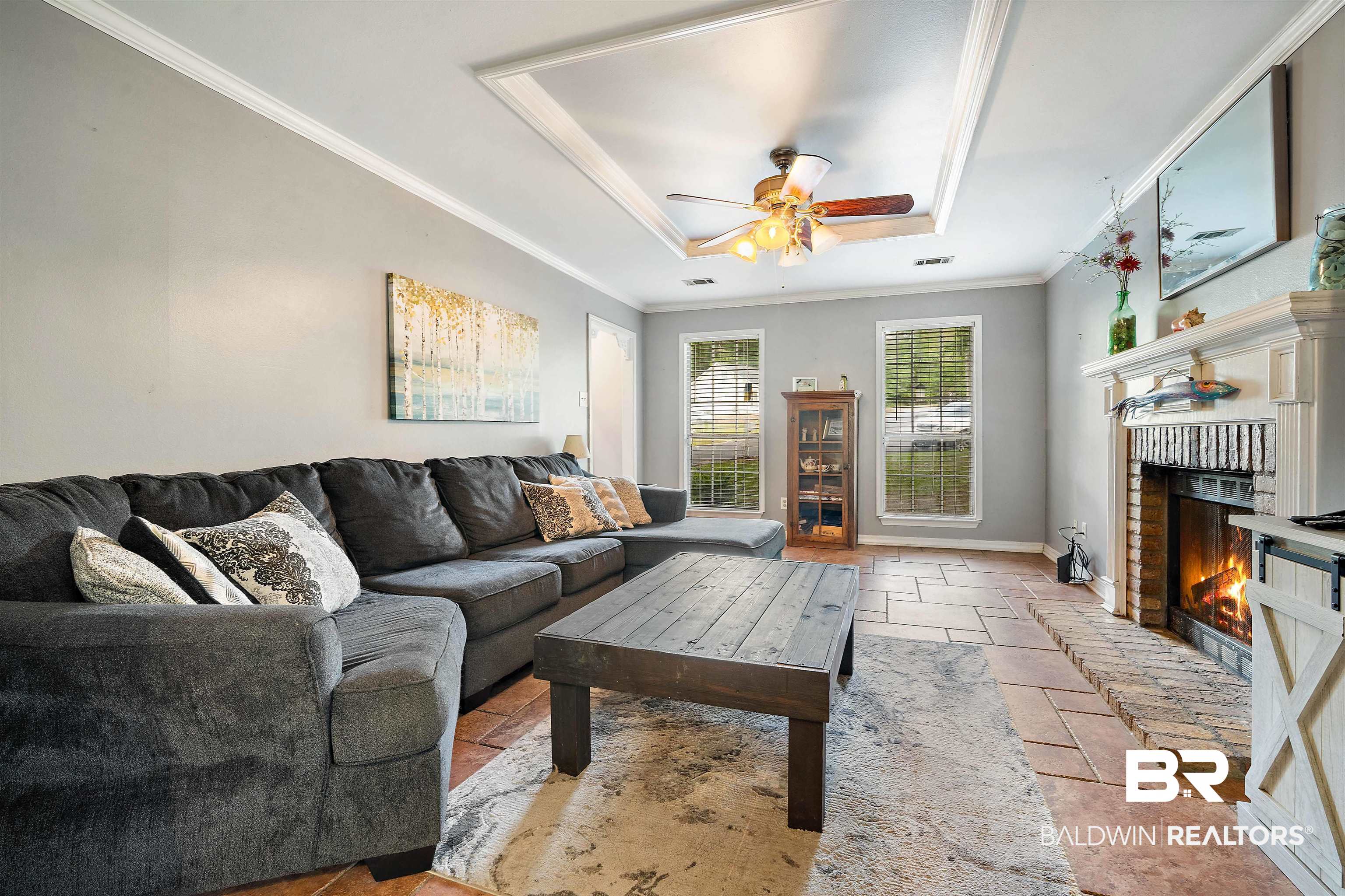 2823 Woodland Road Mobile, AL 36693 - Photo 4 of 29 Living room featuring ceiling fan, a tray ceiling, a fireplace, baseboards, and ornamental molding